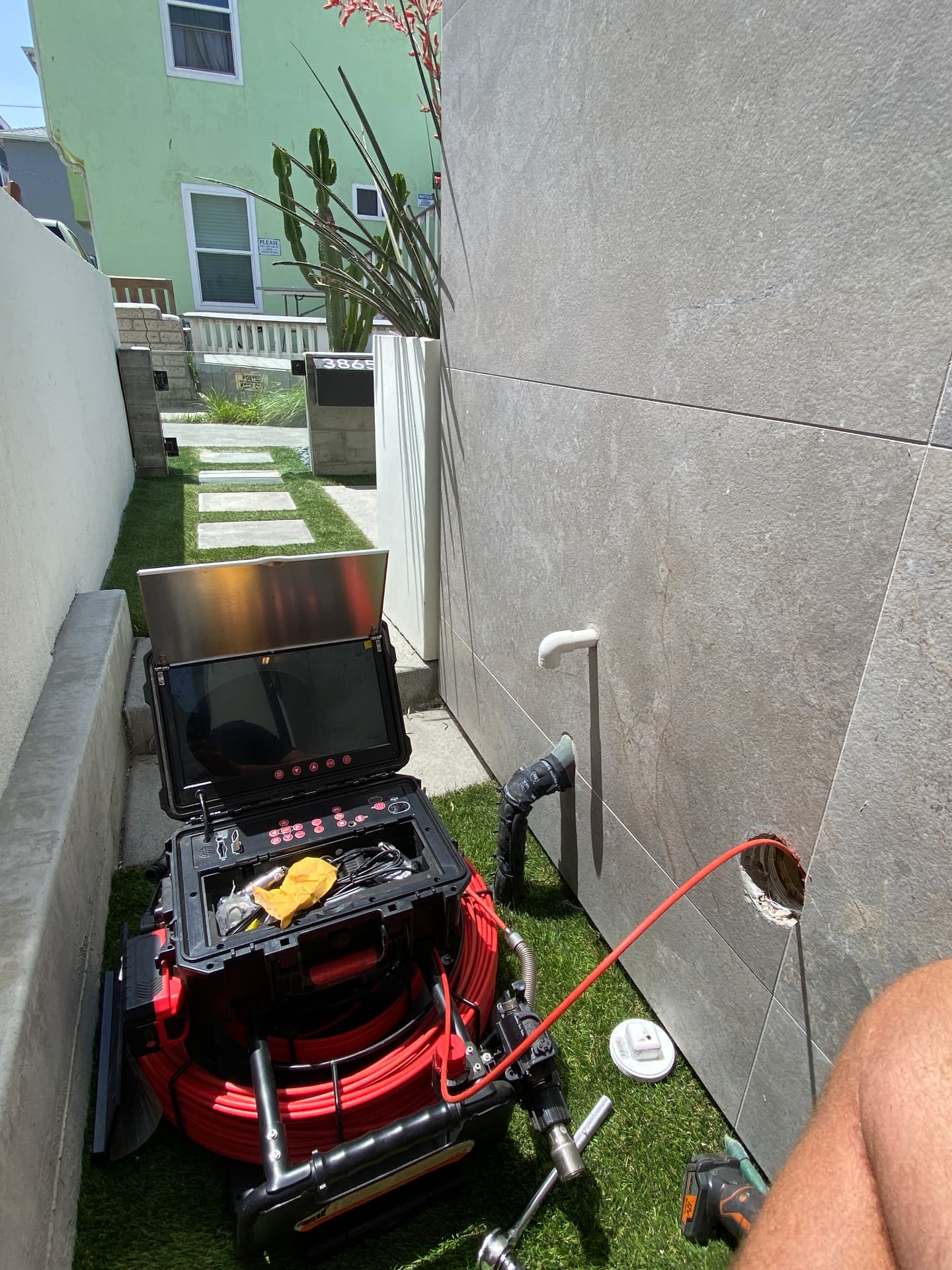 Sewer camera equipment running a line through a wall access point at a coastal San Diego home